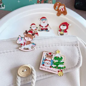 Close-up of adorable Christmas enamel pins featuring Santa and reindeer on a beige fabric bag.