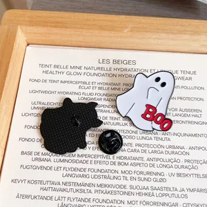 Close-up view of a cute white ghost enamel pin with red Boo text for Halloween accessories