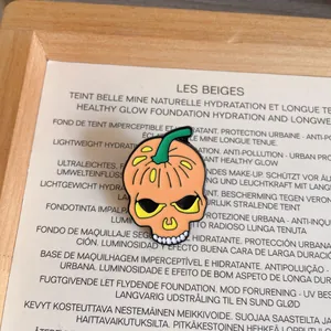 Detailed view of a Halloween pumpkin skull enamel pin featuring vibrant orange and yellow colors