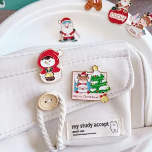 Detail view of cute Christmas enamel pins featuring Santa and snowman on a cream pencil case
