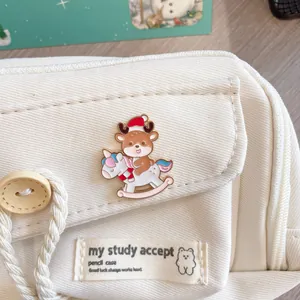 Close-up detail of a cute reindeer Christmas enamel pin on a white canvas pencil case