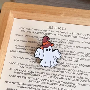 Close-up detail shot of a white Halloween ghost enamel pin wearing a brown witch hat.
