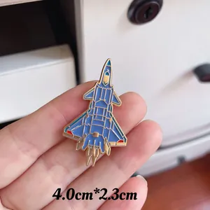 Blue and gold enamel fighter jet brooch showing size of 4.0cm by 2.3cm held in hand