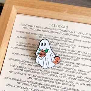 Detailed macro view of a cute Halloween ghost enamel pin holding flowers and pumpkin