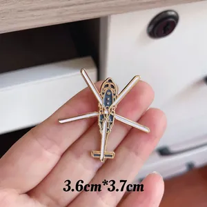 Detail shot of a white helicopter enamel pin measuring 3.6cm by 3.7cm on hand