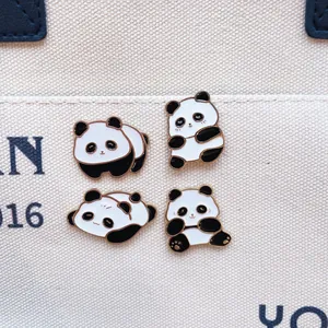 Vista dettagliata di quattro simpatiche spille smaltate a panda su una borsa di tela