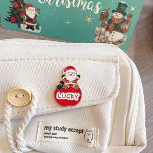 Detailed view of a Santa Claus lucky enamel pin attached to a white canvas pencil case.