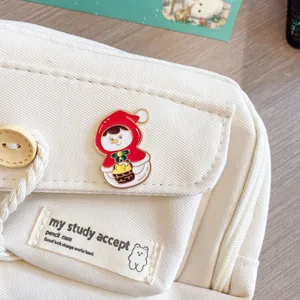 Detailed close-up of a festive snowman enamel pin attached to a cream corduroy bag