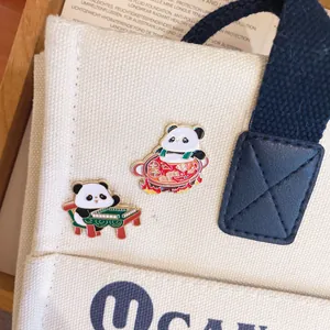 Primo piano di graziose spille in smalto a forma di panda con disegni di hotpot e mahjong.