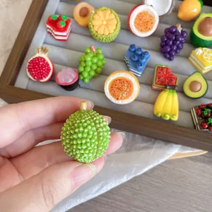 Detailed macro view of a realistic 3D green durian fruit resin brooch held by hand.