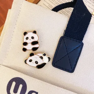 Primo piano dettagliato di due graziose spille smaltate a panda su borsa di tela bianca