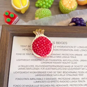 Close-up of a realistic resin pomegranate brooch showing its 3D texture and size details