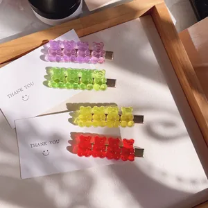 Close-up of four colorful transparent gummy bear hair clips in a wooden tray