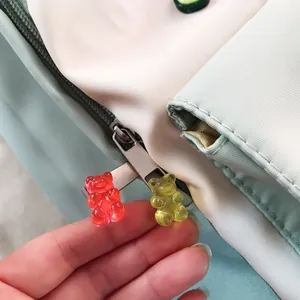 Close-up detail of cute red and yellow gummy bear resin pins on a backpack zipper