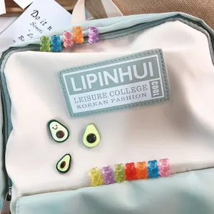 Close-up of colorful gummy bear and avocado brooch pins on a cute schoolbag decor