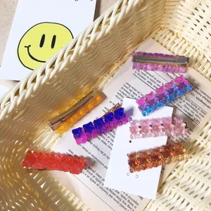 Close-up detail of colorful gummy bear hair clips with glitter sequins inside a woven basket