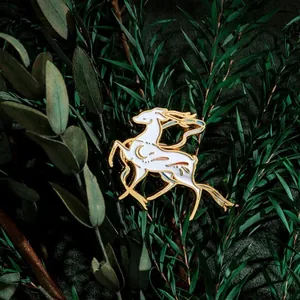 Mythical white deer enamel pin with gold plating on dark green leaves background