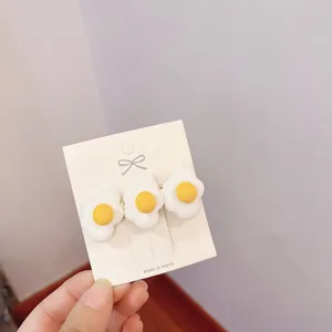 Close-up of three cute simulation poached egg hair clips on display card
