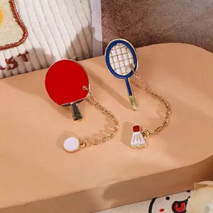 Detailed view of red ping pong and blue badminton racket enamel pins with chain charms