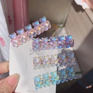 Detailed view of four colorful iridescent gummy bear hair clips mounted on a white display card