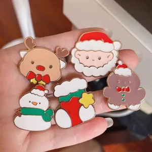 Close-up of five cartoon Christmas enamel pins featuring Santa, reindeer and snowman