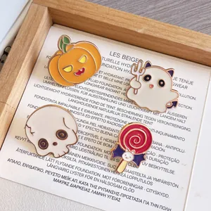 Primo piano di simpatiche spille di Halloween in smalto con zucca, fantasma e teschio.