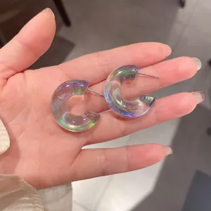 Primo piano di orecchini a cerchio in acrilico a forma di C con riflessi iridescenti