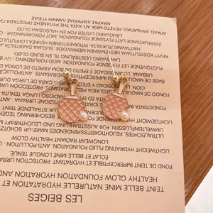 Detalle de pendientes de raqueta de ping pong rosa con perla en un fondo beige