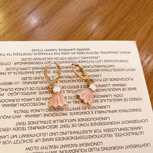 Primer plano de pendientes de aro con volante de esmalte rosa y blanco en tarjeta