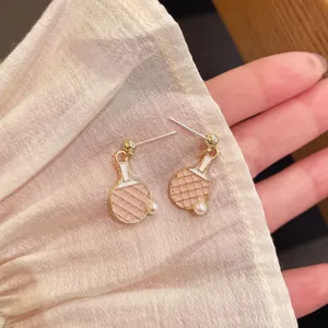 Detalle de pendientes de raqueta de ping pong con esmalte rosa y pequeñas perlas