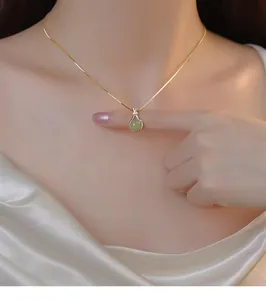 Macro view of a luxury gold lucky bag pendant necklace featuring green Hetian jade stone