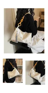 Detailed view of cream Chinese style brocade underarm bag with tassel accessory.
