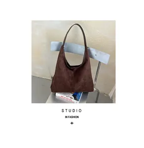 Braune Retro-Wildleder-Hobo-Schultertasche auf einem minimalistischen Studio-Stuhl
