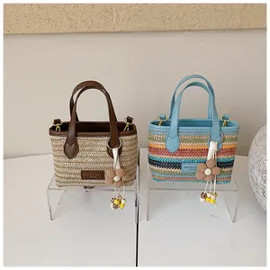 Detailansicht von handgefertigten Strohtaschen in Beige und bunten Regenbogenfarben.