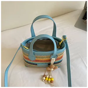 Detailansicht einer bunten handgewebten Stroh-Eimertasche mit hellblauen PU-Lederriemen