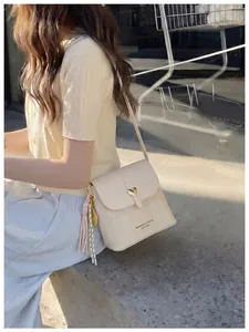 Close-up of a beige textured crossbody bucket bag with heart-shaped gold buckle.