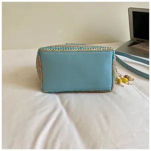 Detailansicht des blauen Bodens und der bunten Webstruktur einer Sommer-Strohtasche.