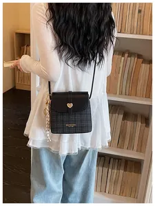Stylish women's plaid bucket crossbody bag with a heart-shaped clasp in a library view