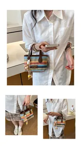 Modell hält eine bunt gestreifte Strohtasche, ideal für den Sommerurlaub am Strand.