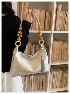 Detail view of Neo-Chinese style floral embroidered bag with wooden bead handle.