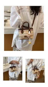 Detailansicht einer gewebten Strohtasche mit Blumenanhänger und Leder-Schultergurt