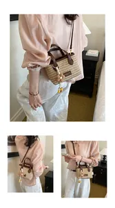 Detailansicht der handgefertigten Stroh-Eimertasche mit Blumenanhänger und Lederriemen