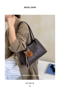 Close-up detail of a vintage brown Maillard tote bag featuring a cute bear plush charm