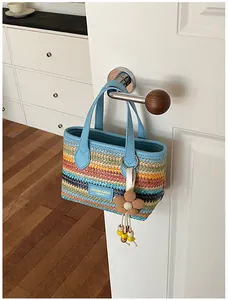 Detailansicht einer handgefertigten Stroh-Strandtasche mit bunten Regenbogenstreifen.