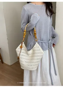 Detailed shot of white laser-cut hollow bag with retro wooden bead strap handles