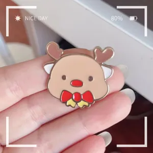 Close-up detail of a cartoon reindeer enamel brooch with red bow tie and alloy finish.
