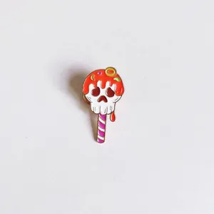 Close-up detail of a cute Halloween skull lollipop enamel pin with red dripping glaze
