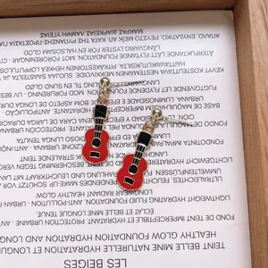 Κοντινό πλάνο με κόκκινα και μαύρα σκουλαρίκια κιθάρα από σμάλτο με βελόνες S925