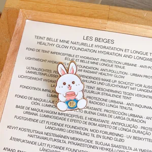 Macro detail of white cartoon rabbit enamel pin holding a blue pot with gold character