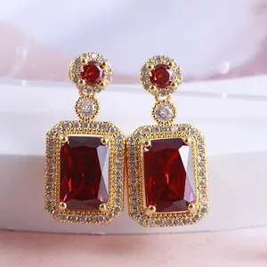 Close-up of elegant red rectangle crystal drop earrings with gold-plated halo setting.